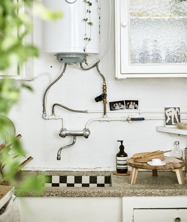 A kitchen sink with boiler unit, closed cupboards and wooden serveware.