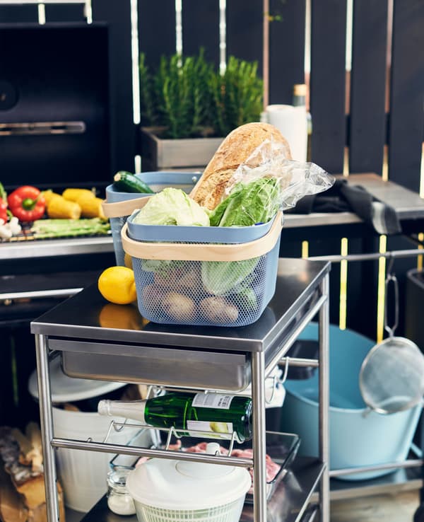 A kitchen trolley with a basket of food on top.