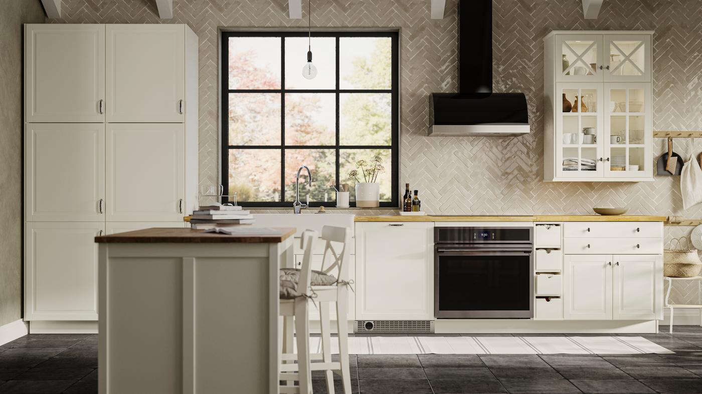 A kitchen with BODBYN doors and drawer fronts in off-white and a TORNVIKEN kitchen island with books on it.