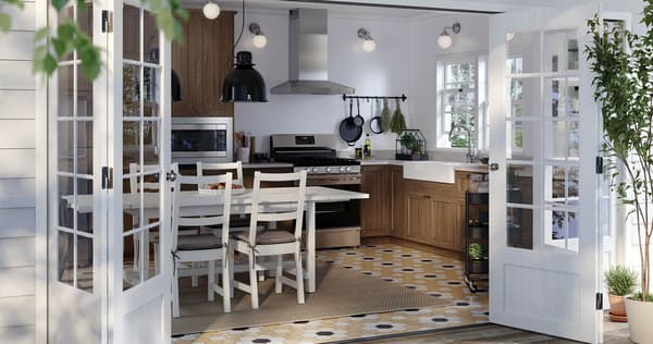 A kitchen with brown fronts and a white table wtih four chairs, with doors open to the patio.