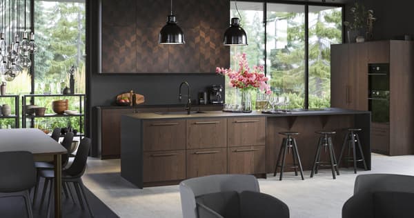 A kitchen with brown fronts and large windows, with two black pendant lamps and a vase of flowers on the kitchen island.