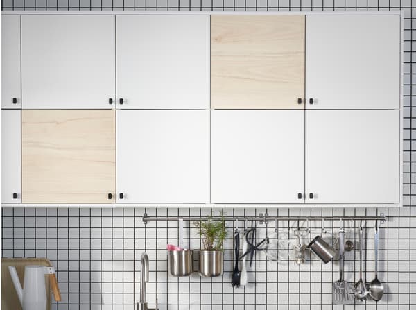 A kitchen with doors in white and light ash effect, two rails in stainless steel and a white watering can.