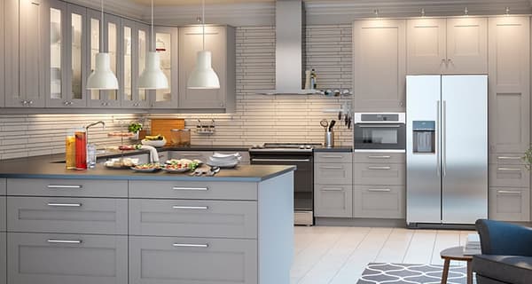 A kitchen with light gray cupboards and a white countertop, with a grey accents and lots of cupboards.