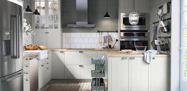 A kitchen with off white cabinets and stainless steel hardware and appliances 
