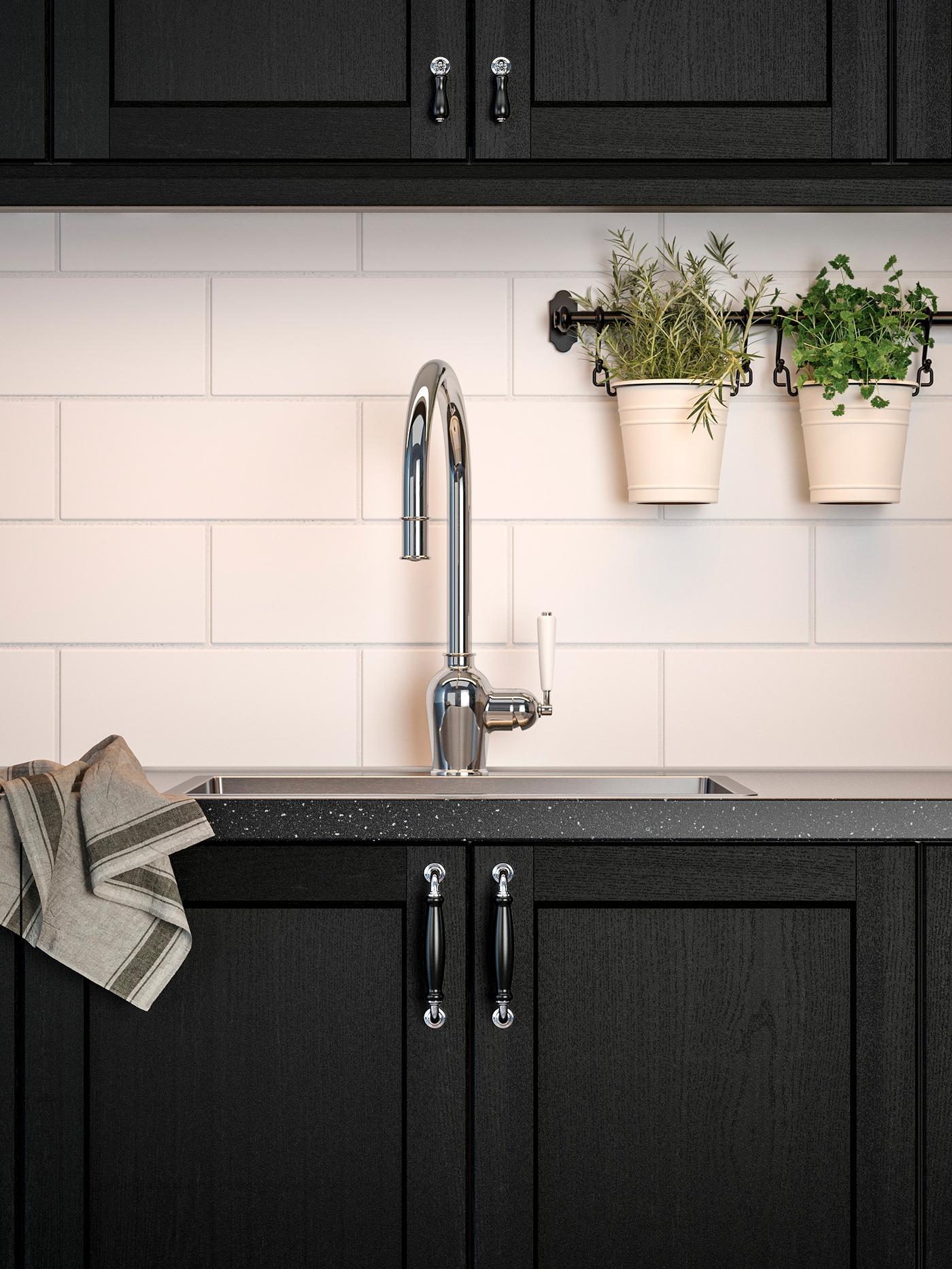 A kitchen with stained black cabinet fronts, a black mineral-effect worktop and a chrome-plated mixer tap.