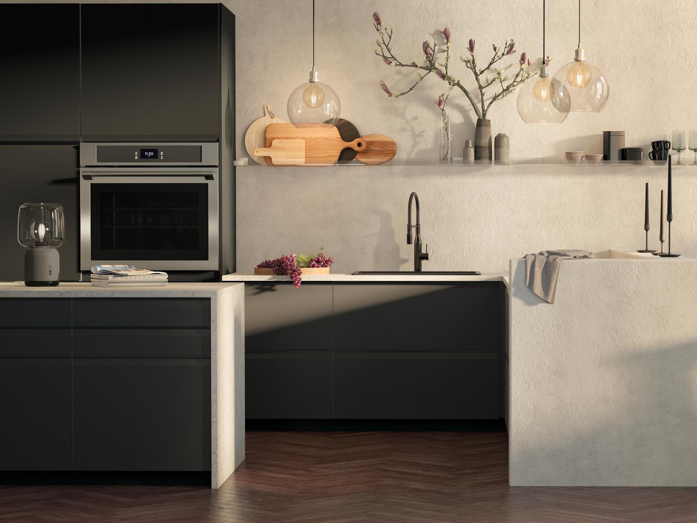 A kitchen with UPPLÖV drawer fronts in matt anthracite, JAKOBSBYN lampshades and a TÄNGBY wall oven in stainless steel.