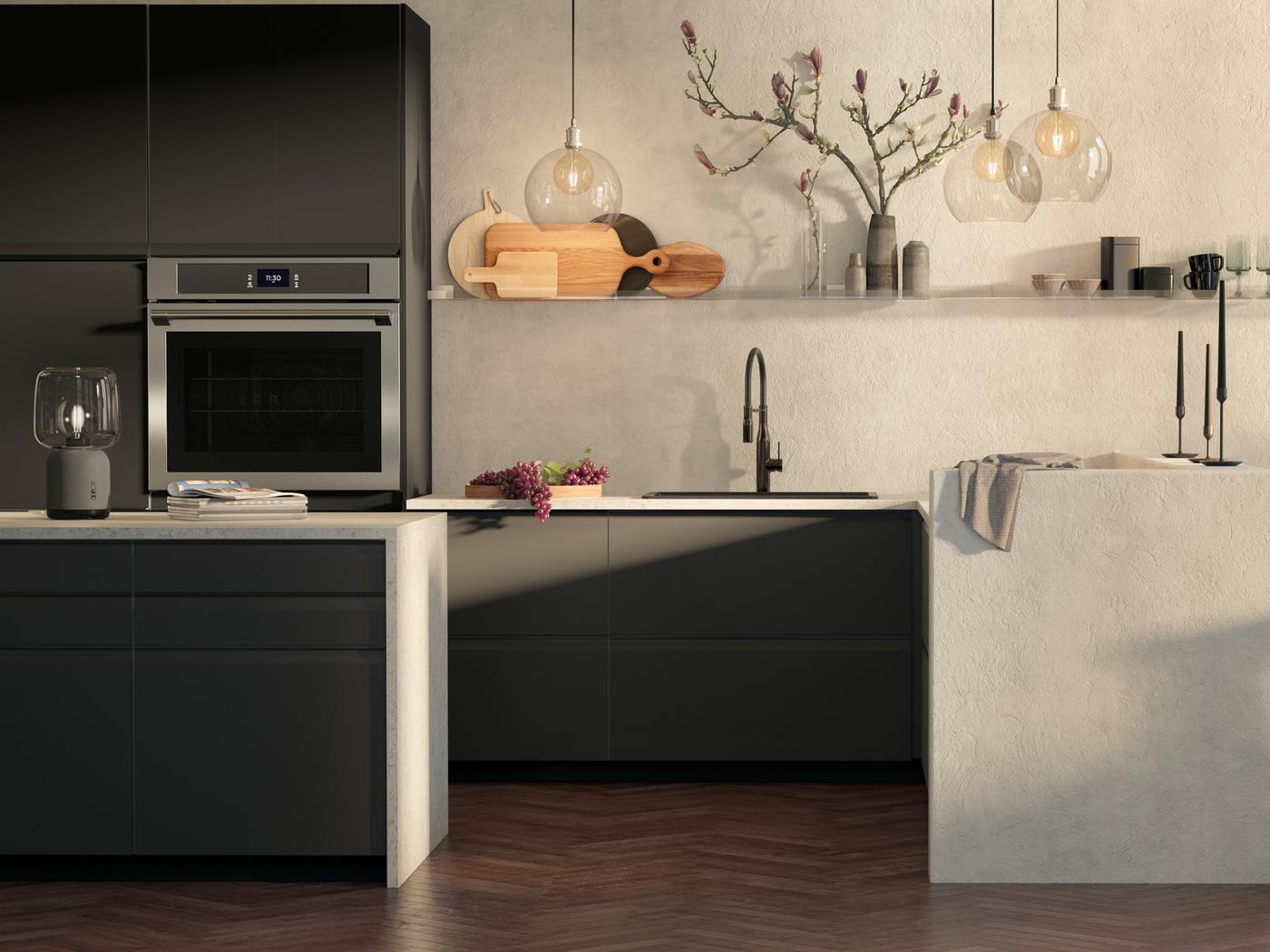A kitchen with UPPLÖV drawer fronts in matt anthracite, JAKOBSBYN lampshades and a TÄNGBY wall oven in stainless steel.