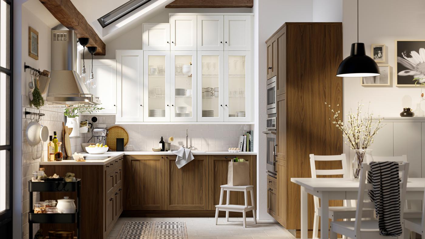 A kitchen with white wood effect ENKÖPING doors and glass doors, plus brown walnut effect ENKÖPING doors and drawer fronts.