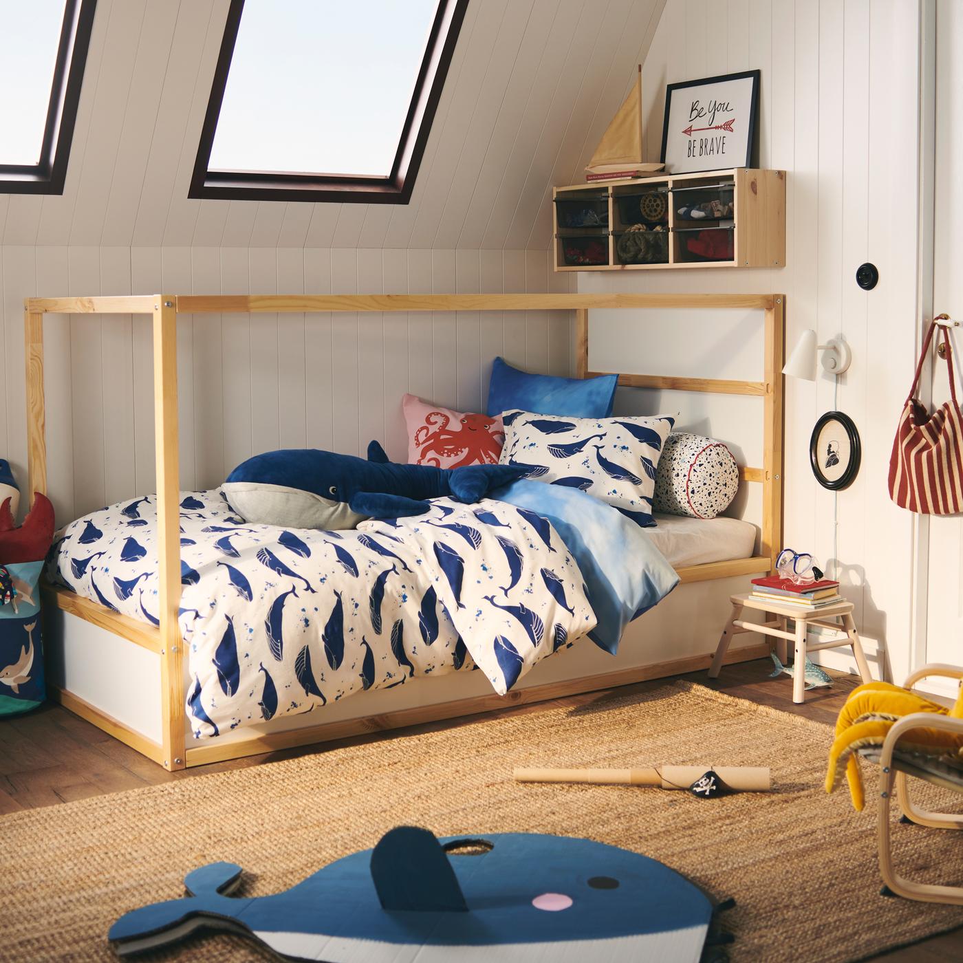 A KURA bed is dressed in a BLÅVINGAD whale duvet cover set; a BLÅVINGAD blue whale soft toy sits on top.