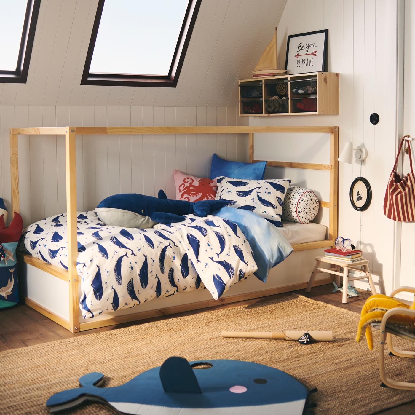 A KURA bed is dressed in a BLÅVINGAD whale duvet cover set; a BLÅVINGAD blue whale soft toy sits on top.