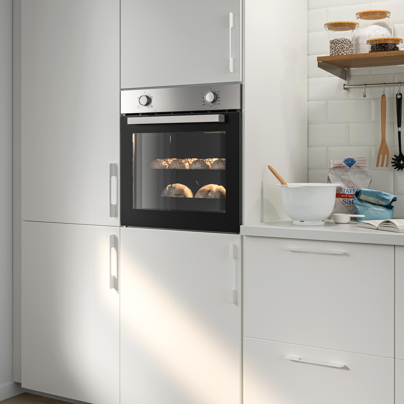 A LAGAN stainless steel oven integrated within a white kitchen with white handles and a white worktop