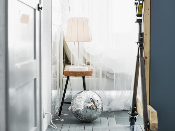 A lamp on a cork stool next to a bed dressed in white textiles, in front: a disco ball. What’s your dream bedroom?
