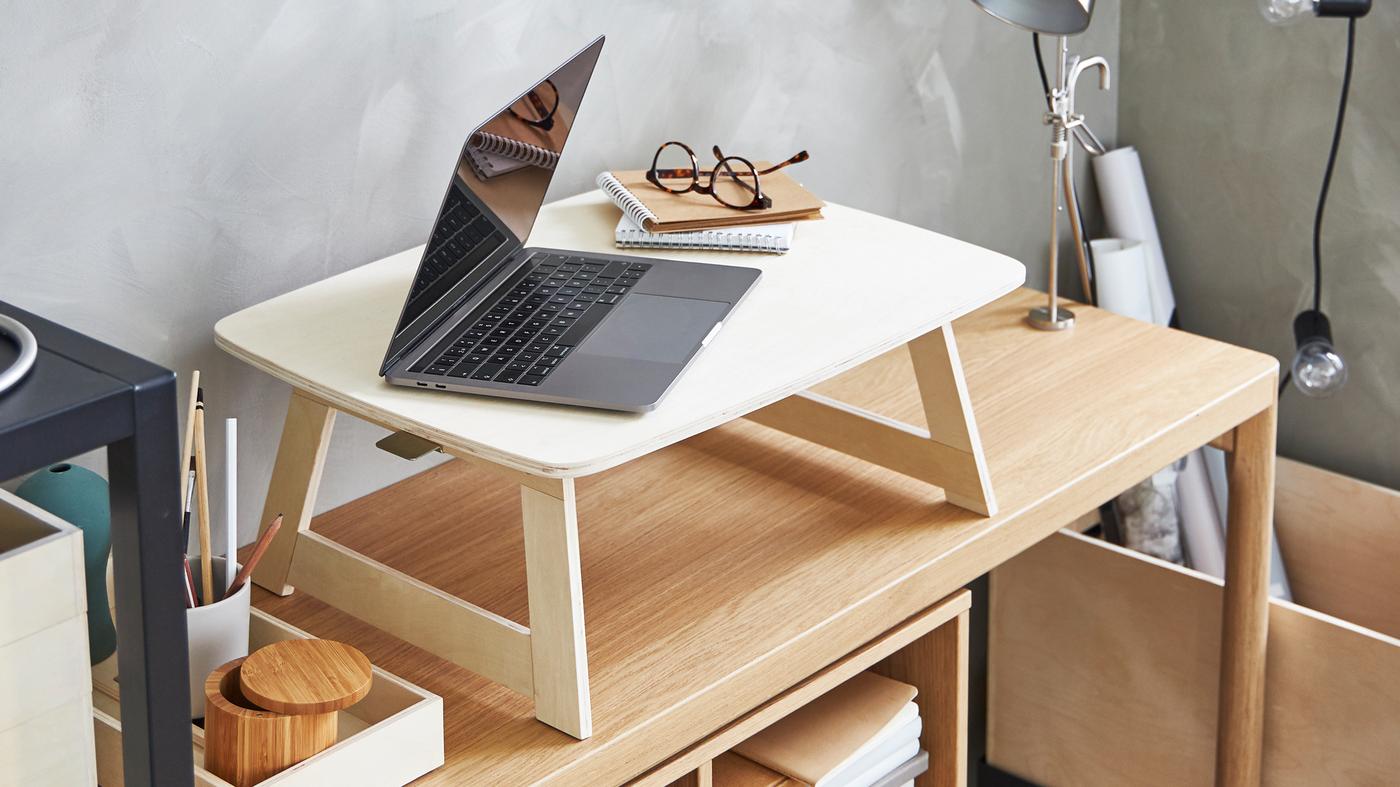 A laptop, notepads and spectacles on a birch plywood, RÅVAROR tray that stands on an oak veneer, RÅVAROR console table.