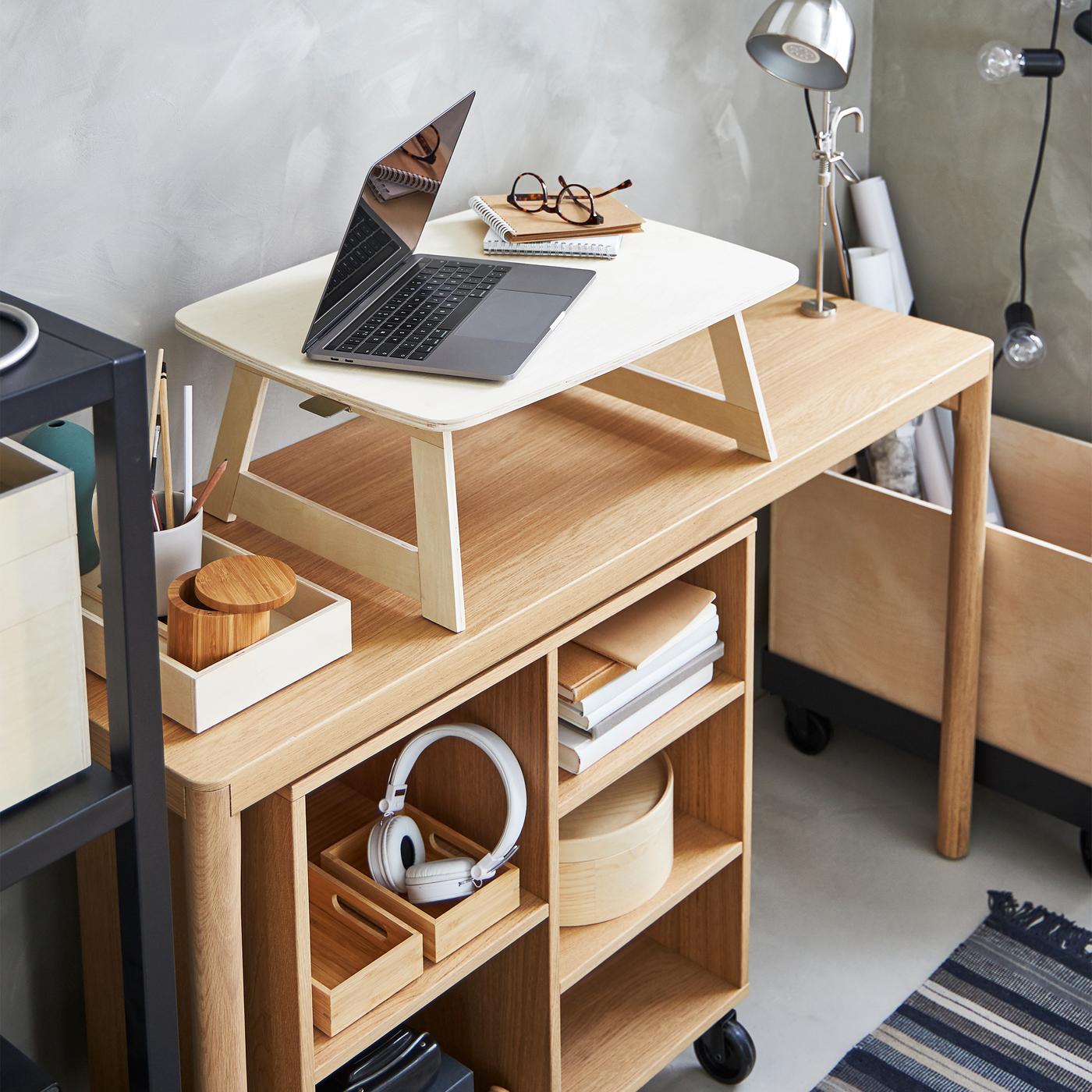 A laptop, notepads and spectacles on a birch plywood, RÅVAROR tray that stands on an oak veneer, RÅVAROR console table.