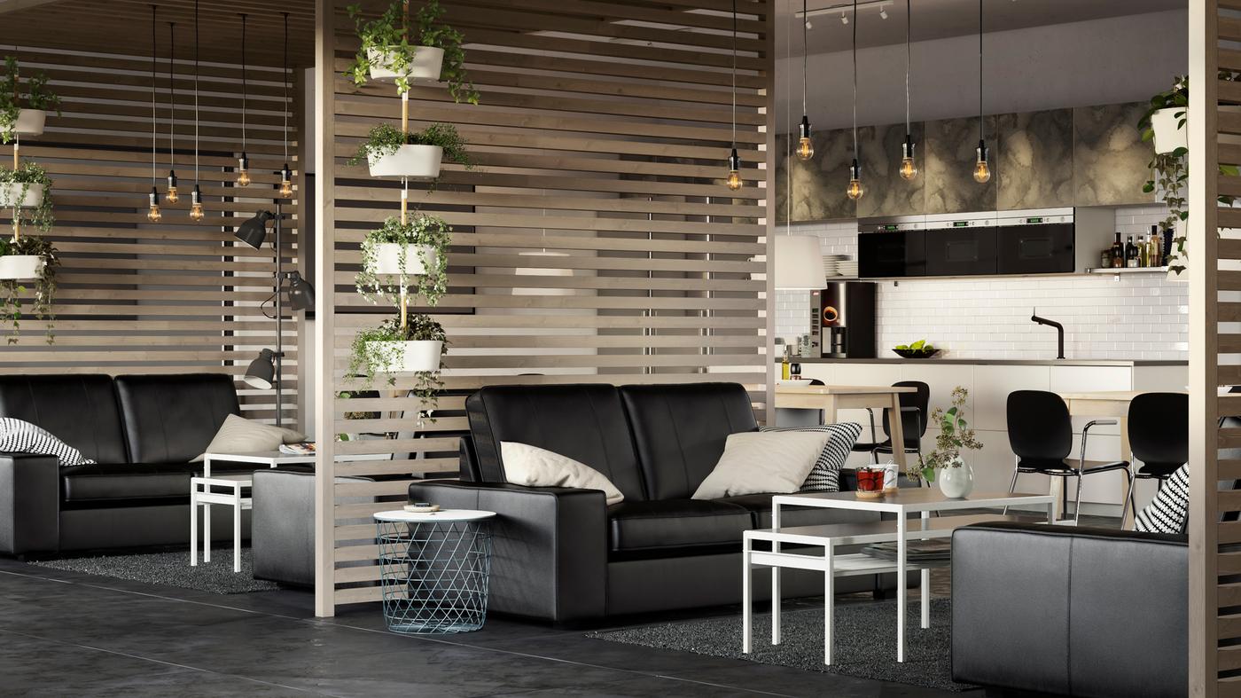 A large airy business office space with KIVIK black leather sofas and slatted wood room dividers.