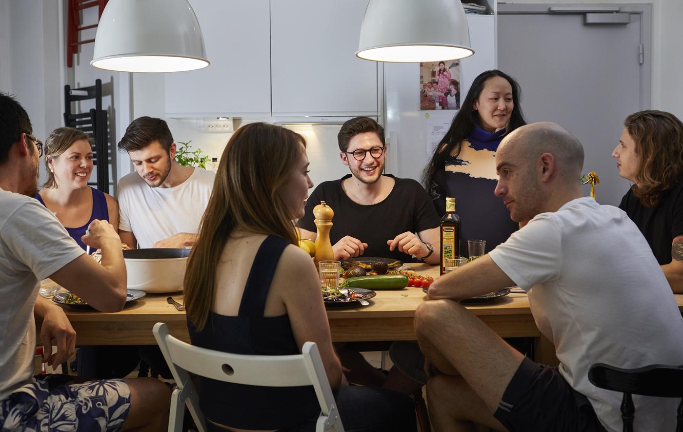 A large group of people eating dinner and chatting around a table.