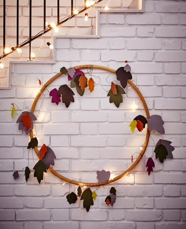 A large ring made into a wall decoration with lighting chains and cut-out paper leaves.