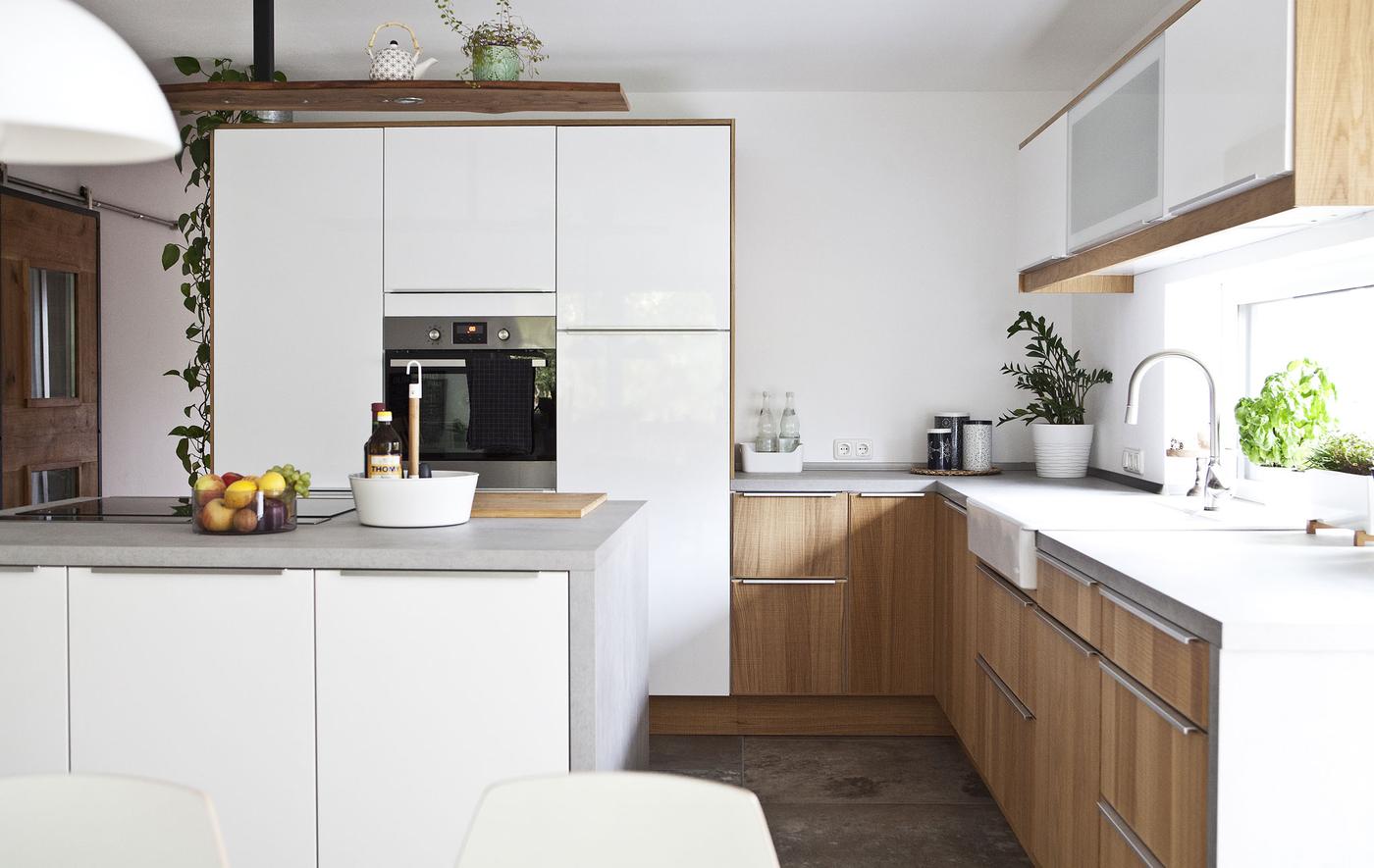 A large white kitchen with a mix of wood cabinet fronts and kitchen island with built-in hob.