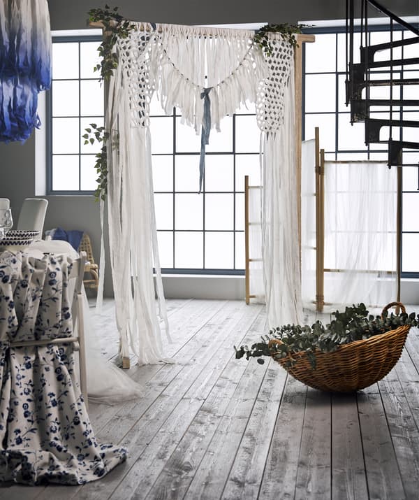 À l’arrière plan, un rideau de mariage réalisé en tissu blanc en coton noué à un paravent en rotin TÄNKVÄRD.