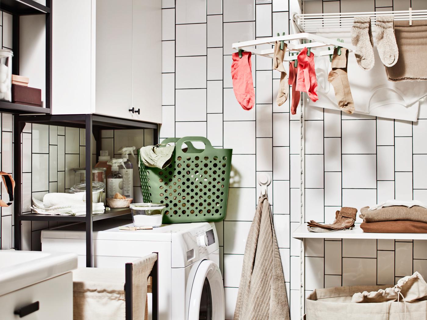 A laundry area with a washing machine, a storage combination for laundry and a SLIBB hang dryer with socks hanging from it.