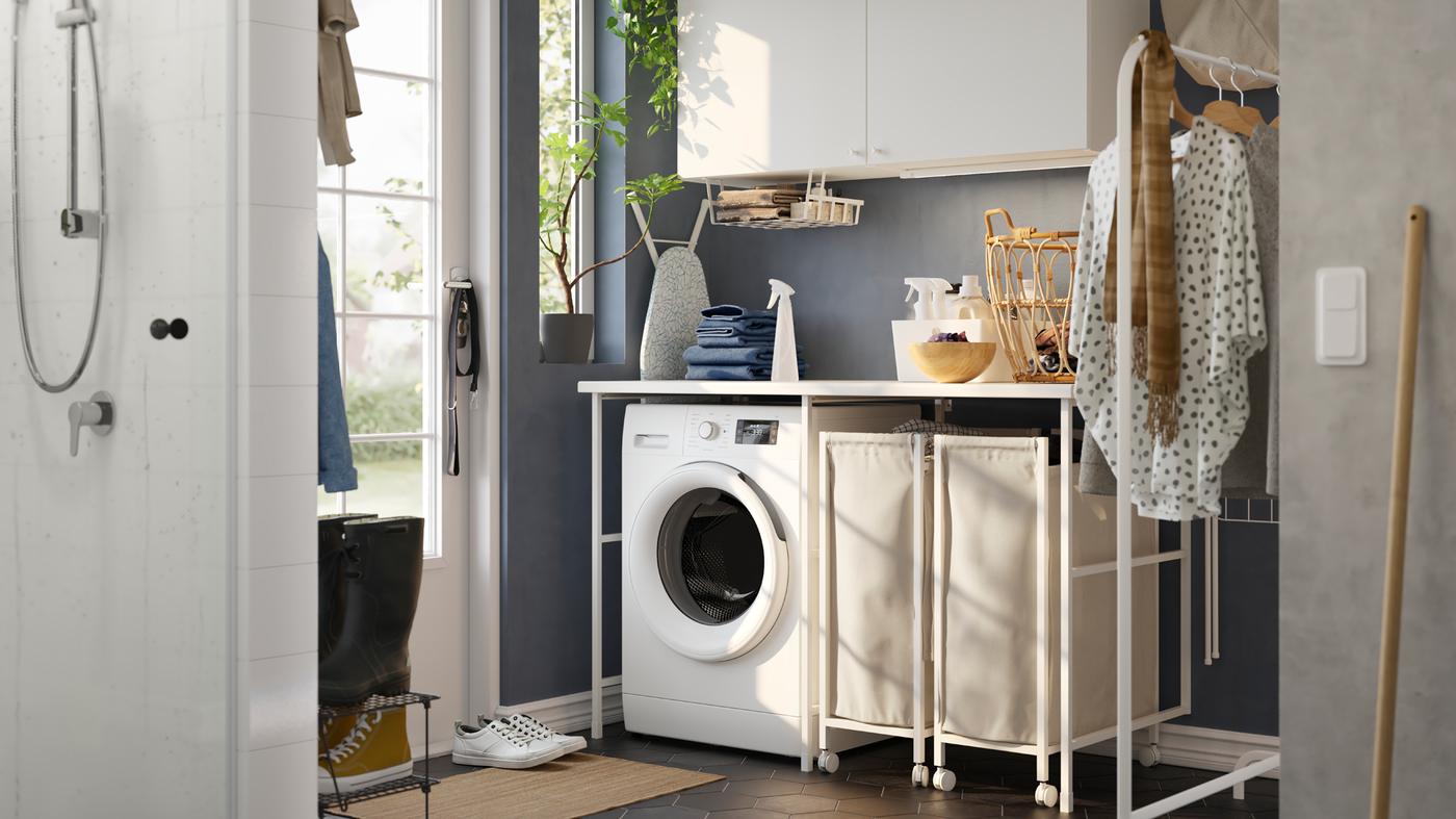 A laundry room with blue walls and a white ENHET storage combination, a washing machine and two laundry baskets on castors.