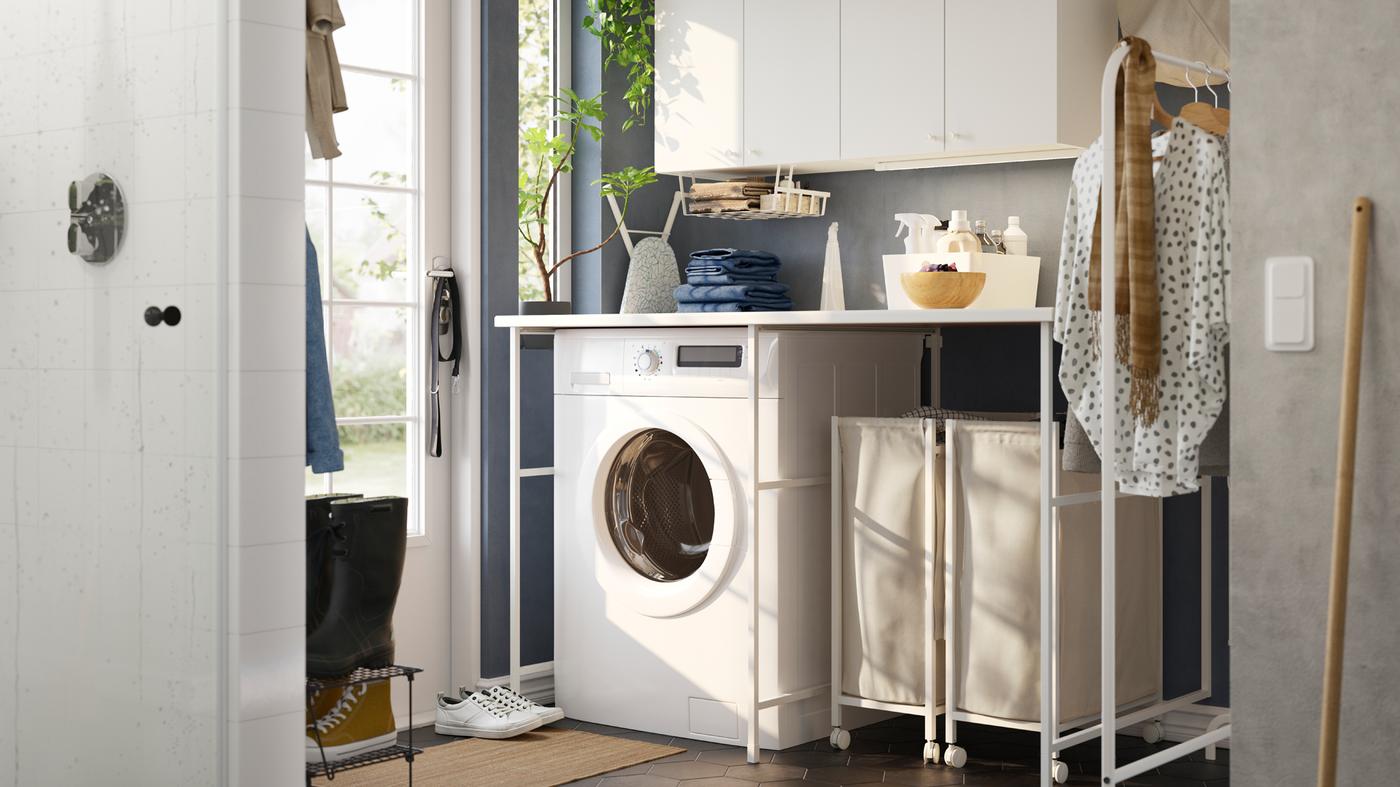 A laundry room with blue walls and a white ENHET storage combination, a washing machine and two laundry baskets on castors.