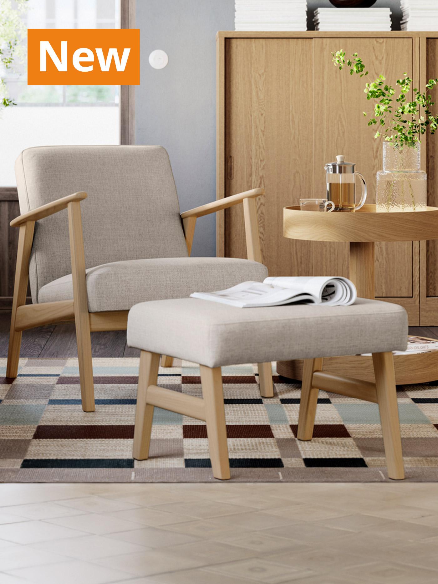 A lifestyle image of a oat effect/off-white EKENÄSET armcahir & footstool in the corner of a living room setting placed on a STOCKHOLM floor rug. Overlaying the image, orange tag that reads 'New' on the top left corner.