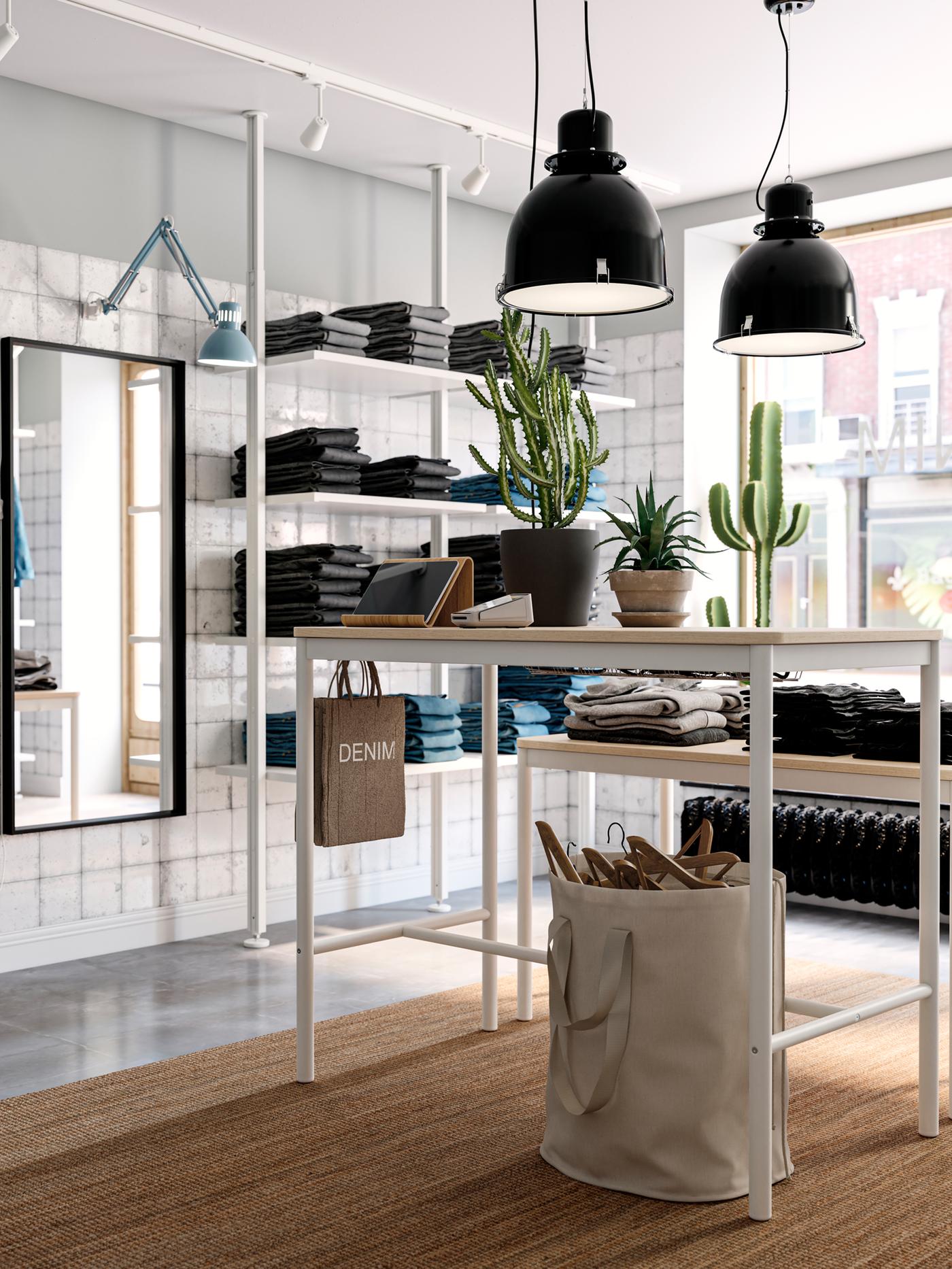 A light, airy store interior with a LOHALS rug and denim garments arranged in white ELVARLI storage combinations.