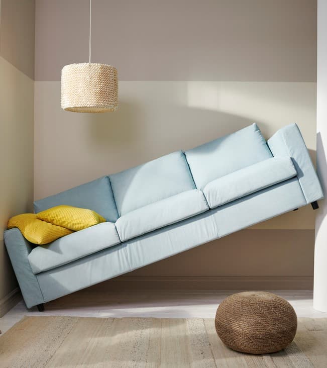 A light blue sofa is suspended between two walls because it is too long to fit in the gap.
