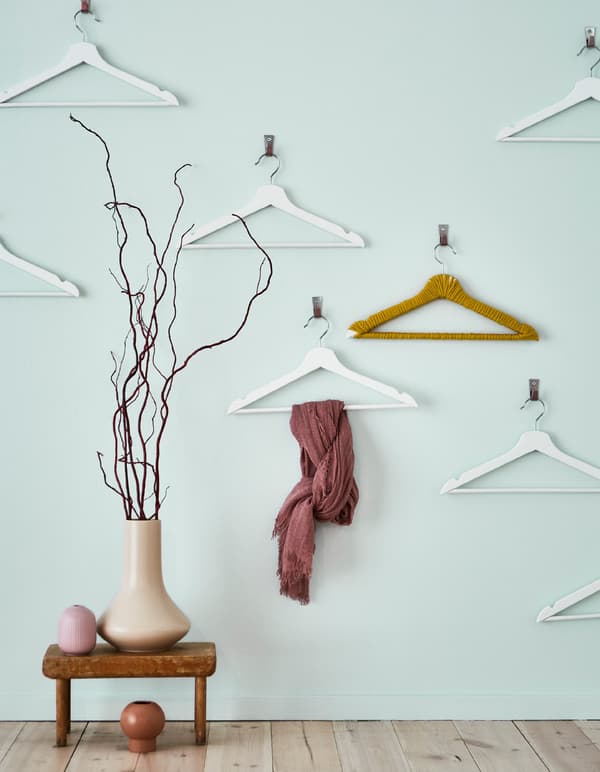 A light blue wall with several hangers on hooks creates visual impact and more opportunities to store or display.
