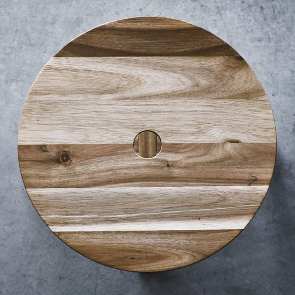 A light brown, wooden, circular piece, laid out on a concrete surface.