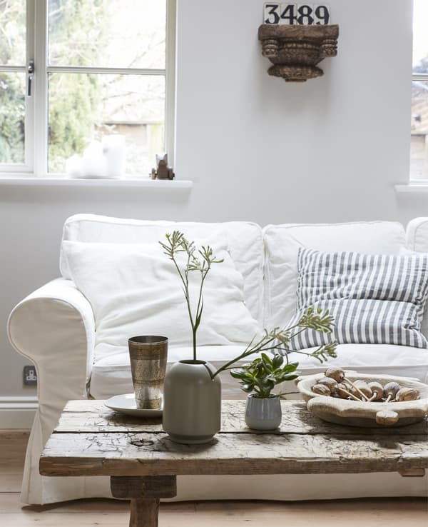 A light-coloured living room with a white sofa and rustic wooden coffee table.