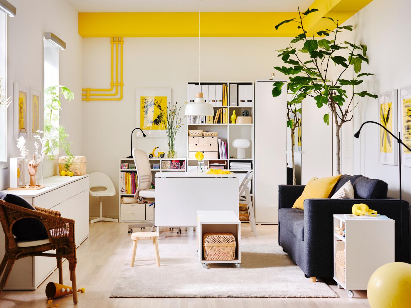 A light living room with bright-yellow accents furnished with white VIHALS storage units and a dark-grey PÄRUP sofa-bed.