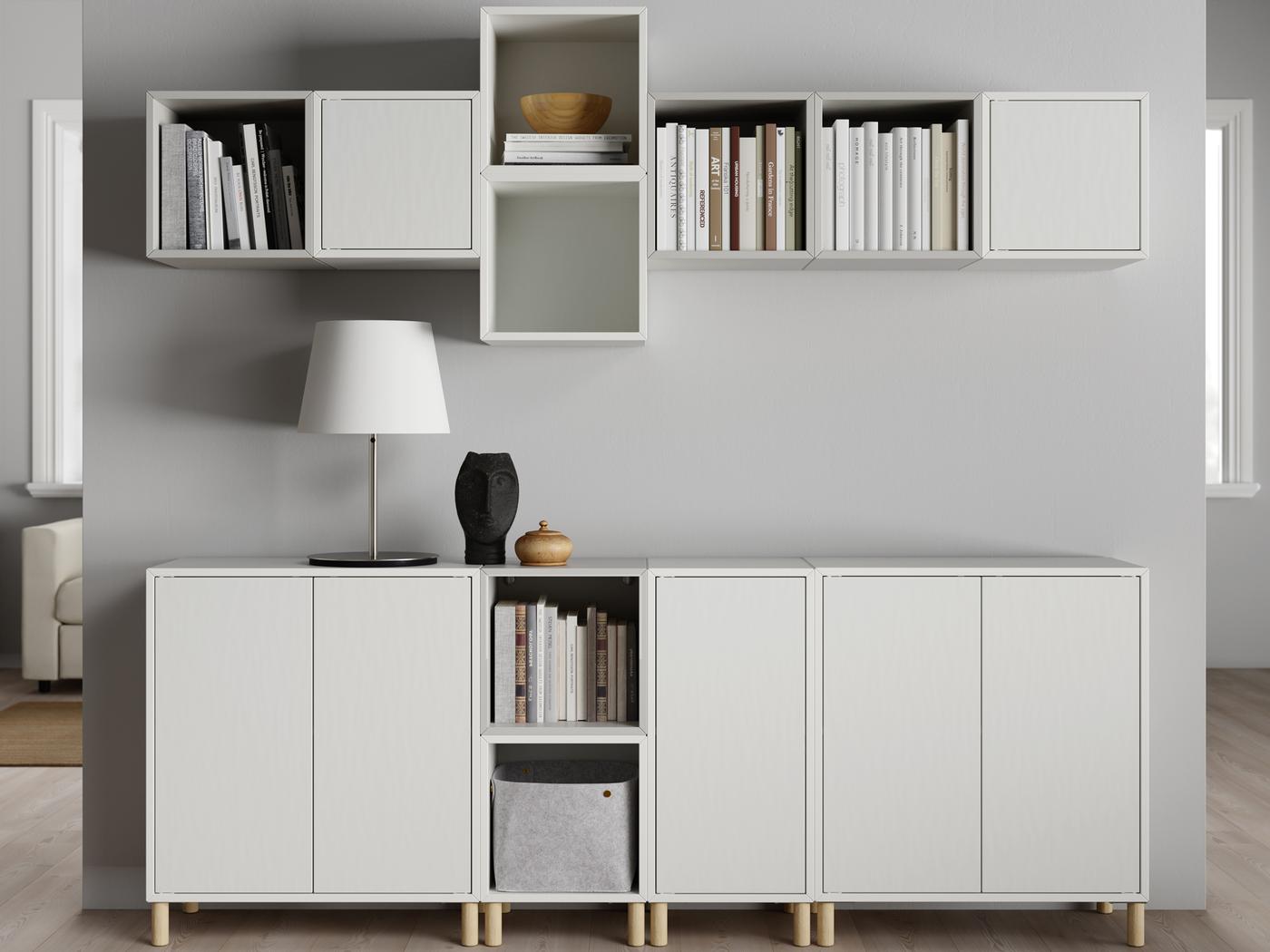 A light living room with rows of white-and-light-grey EKET cabinets arranged on a wall and standing on the floor beneath.