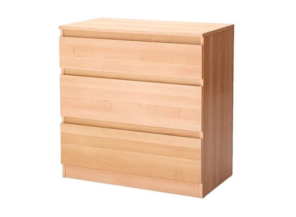 A light wood colored 3 drawer chest against a white background