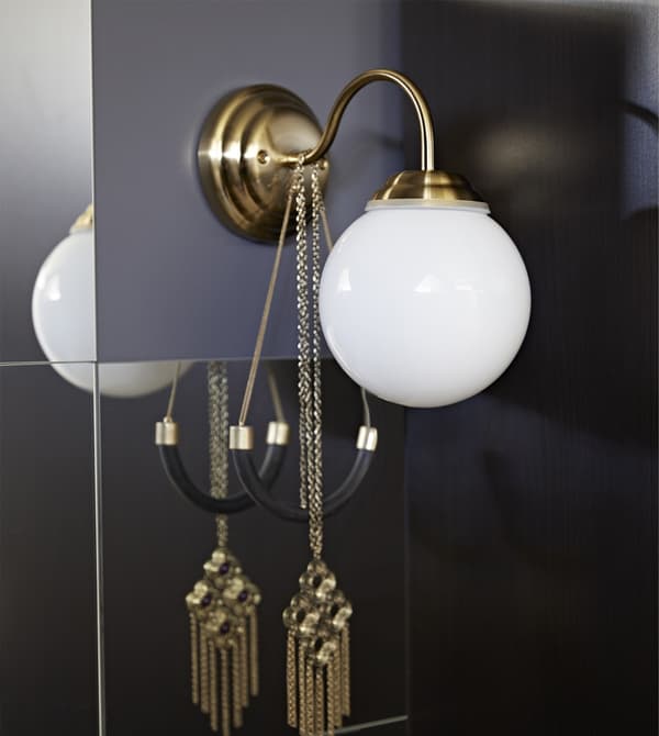 A LILLHOLMEN wall lamp has a brass-colour base, thin rounded neck and white glass globe.