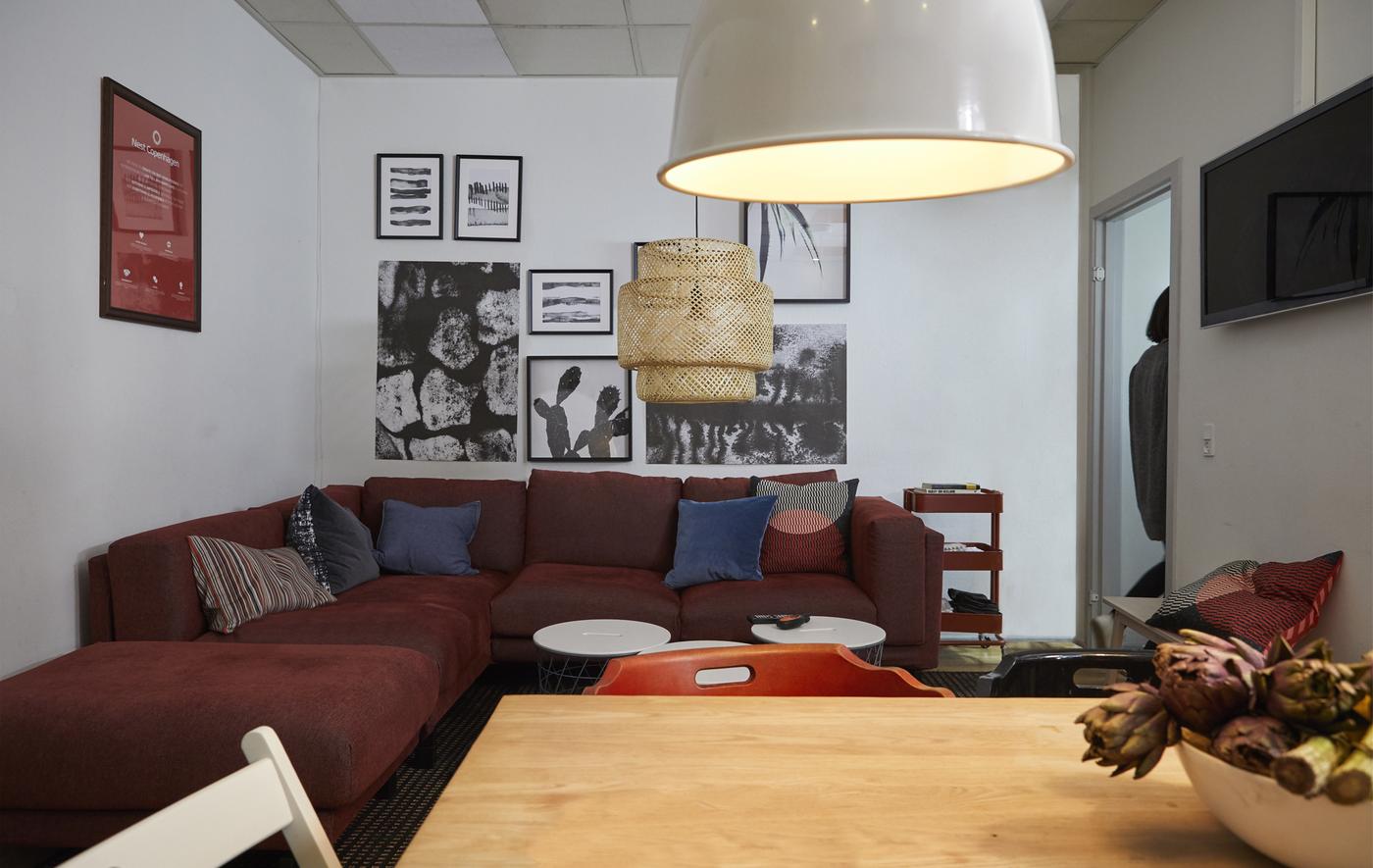 A living area with a large corner sofa, pendant lamps, and a gallery wall of framed art.