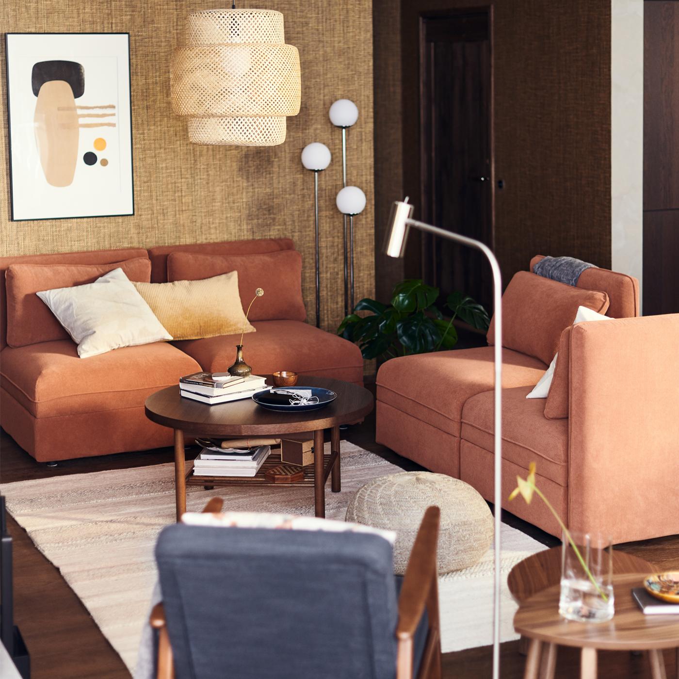 A living area with VALLENTUNA modular sofas in rust below a bamboo SINNERLIG pendant lamp.