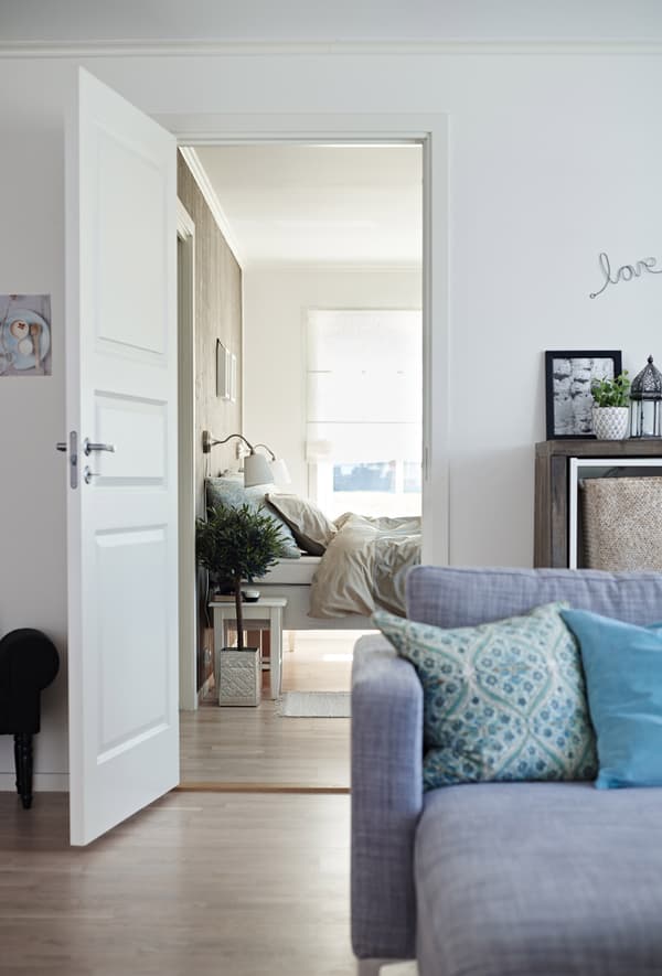 A living room area with a white open door that leads to a bedroom. The neutral tones on the walls make it easy to style.