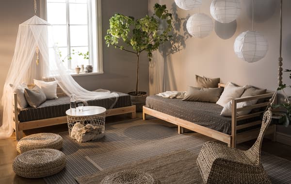 A living room in natural colours and decorated with day beds, paper lamps, woven cushions and plants.