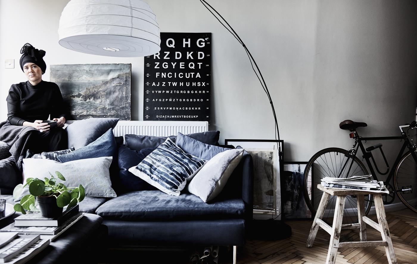 A living room with a dark sofa and lots of cushions.