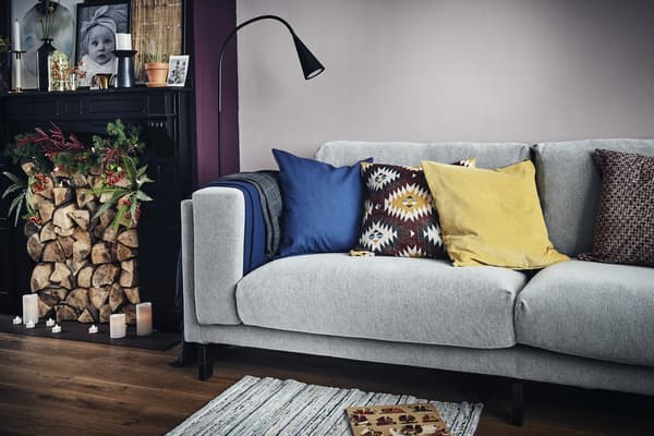 A living room with a grey sofa, lighting and a logfilled fireplace.