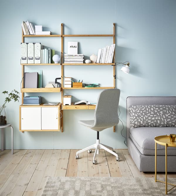 A living room with a sofa and a wall of modern bamboo shelves including one shelf that’s a desk. 