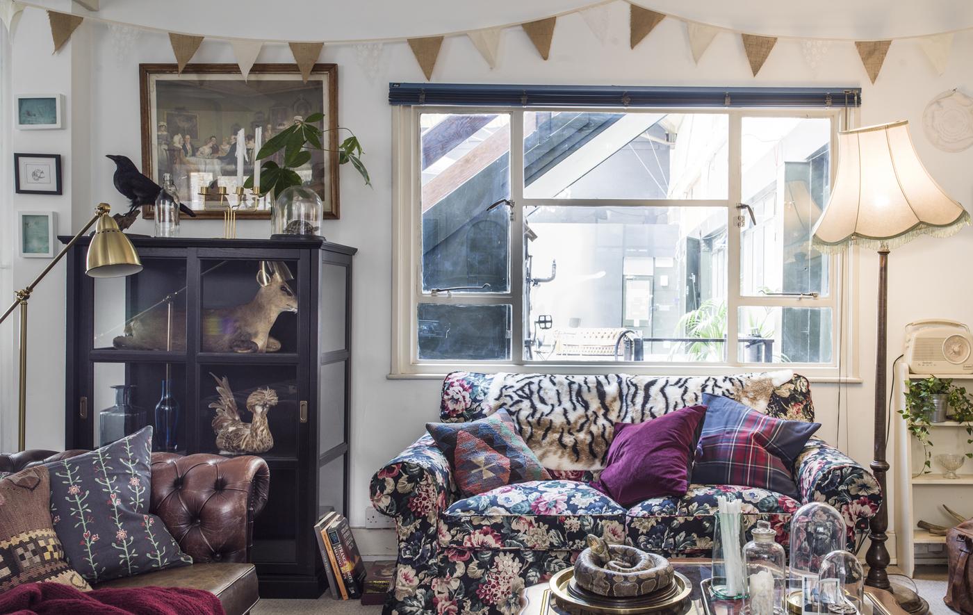 A living room with floral sofa, display cabinets and lamps.