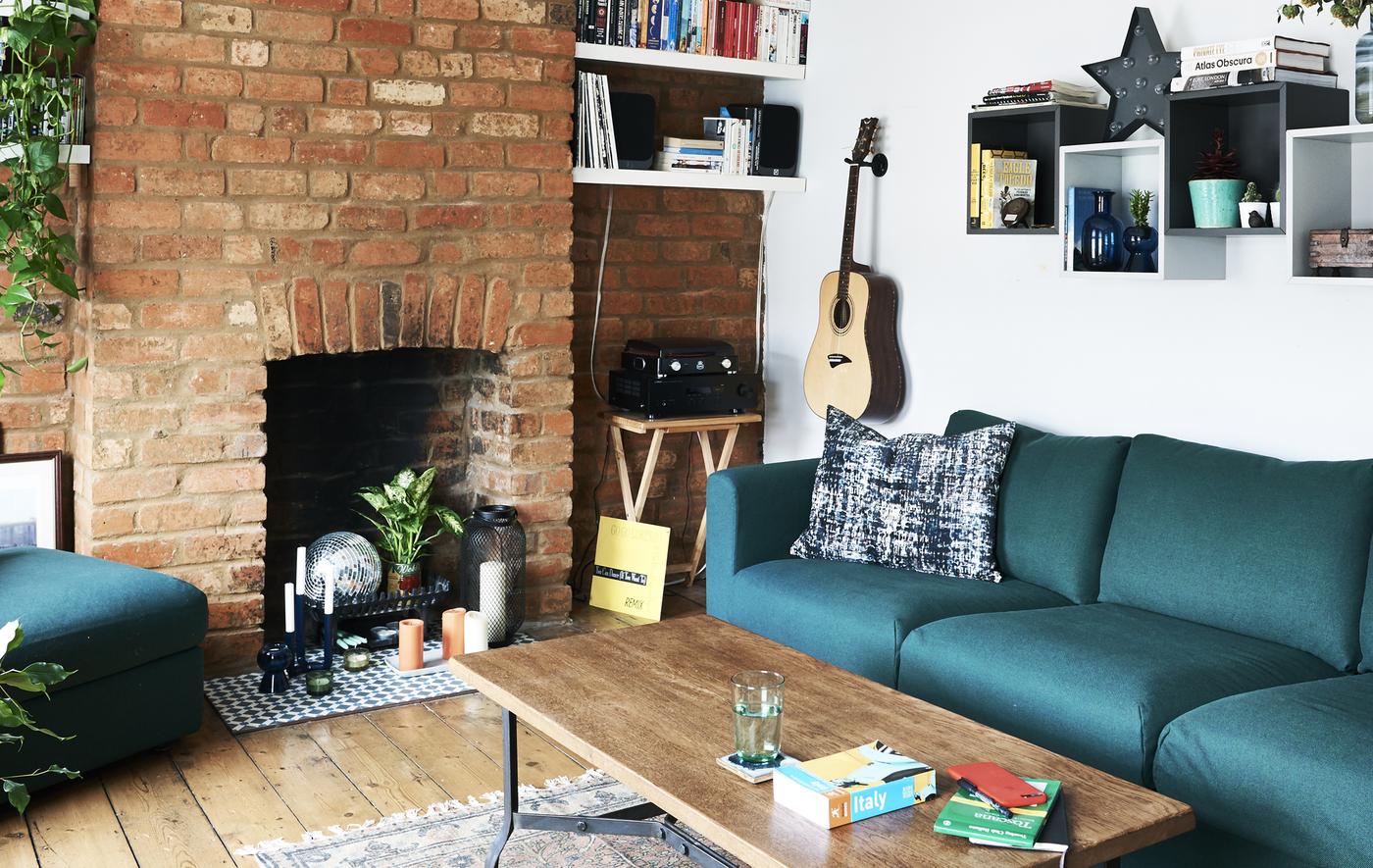 A living room with green sofa and exposed brick wall.