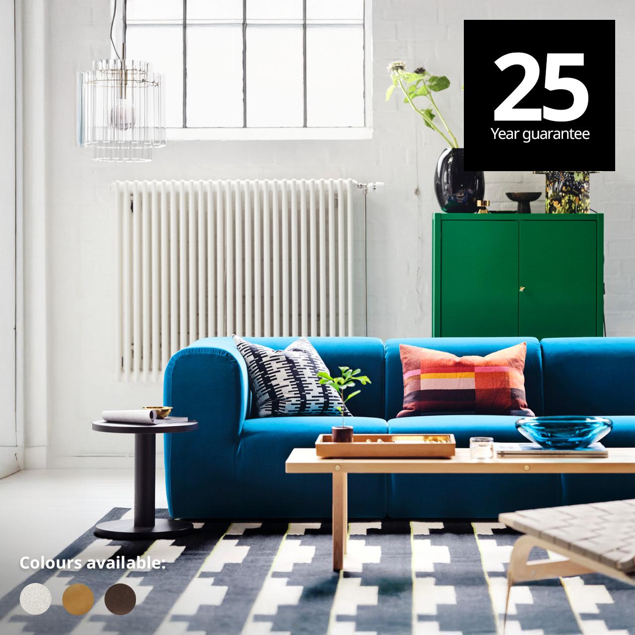 A living room with STOCKHOLM 2025 collection; a STOCKHOLM 2025 3-seat sofa in alhamn dark turquoise, a STOCKHOLM side table and a STOCKHOLM coffee table on a STOCKHOLM rug. A 25-year guarantee tag is placed over the image at the top right corner. White text overlay image that reads "Colours available:" with the colour swatch of Djurmo greywhite, Alhamn beige and Alhamn dark brown.