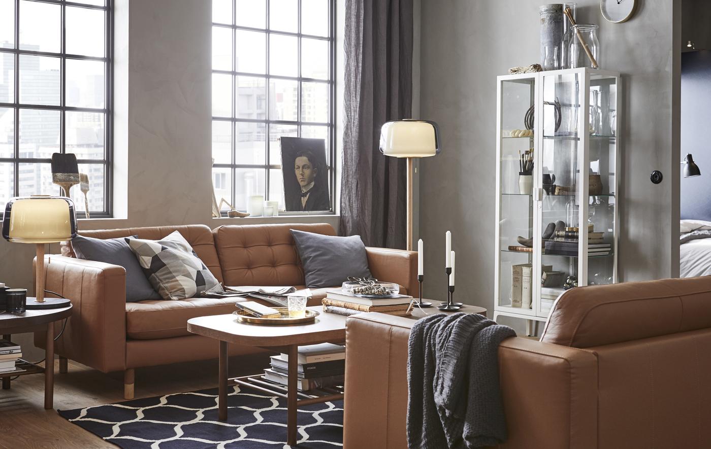A living room with two brown leather sofas, a coffee table, a glass display cabinet, and lamps.