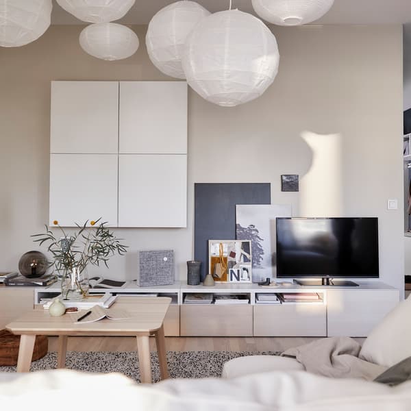 A living room with white cabinets on the wall and an IKEA BESTÅ TV bench.