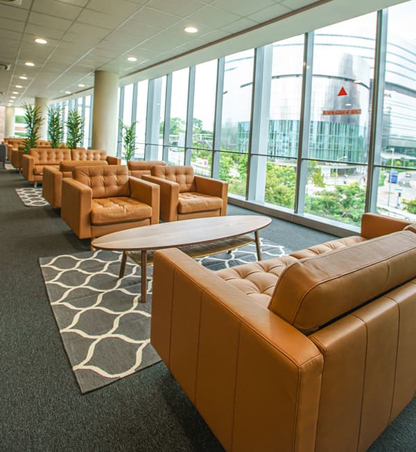 A lounge area featuring mustard yellow sofas placed facing each other on top of a grey and white rug and an oval table.