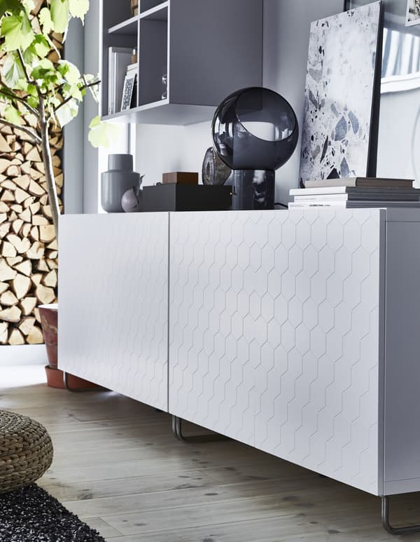 A low white storage unit with honeycomb-patterned door.
